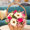 Cesta de mimbre con gerberas amarillentas, rosas fucsias y alstroemerias rosadas